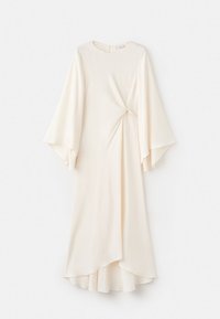 Rochie lungă crem cu mâneci evazate în formă de clopot, decolteu rotund și detaliu strâns la talie, atârnând pe un fundal alb.