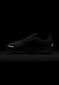 Baskets de sport noires avec une tige texturée, des accents réfléchissants et une semelle rembourrée. Caractéristiques d'une silhouette lisse et d'un système de laçage.