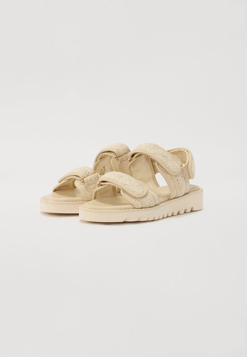Sandalias beige con amplias correas texturizadas, cierres de velcro ajustables y suela estriada para un mejor agarre, diseñadas para la comodidad y el soporte.