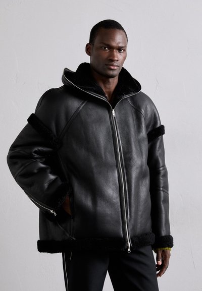 Black leather jacket with a fur-lined collar, featuring zippered front, side pockets, and black fur accents on sleeves and hem.