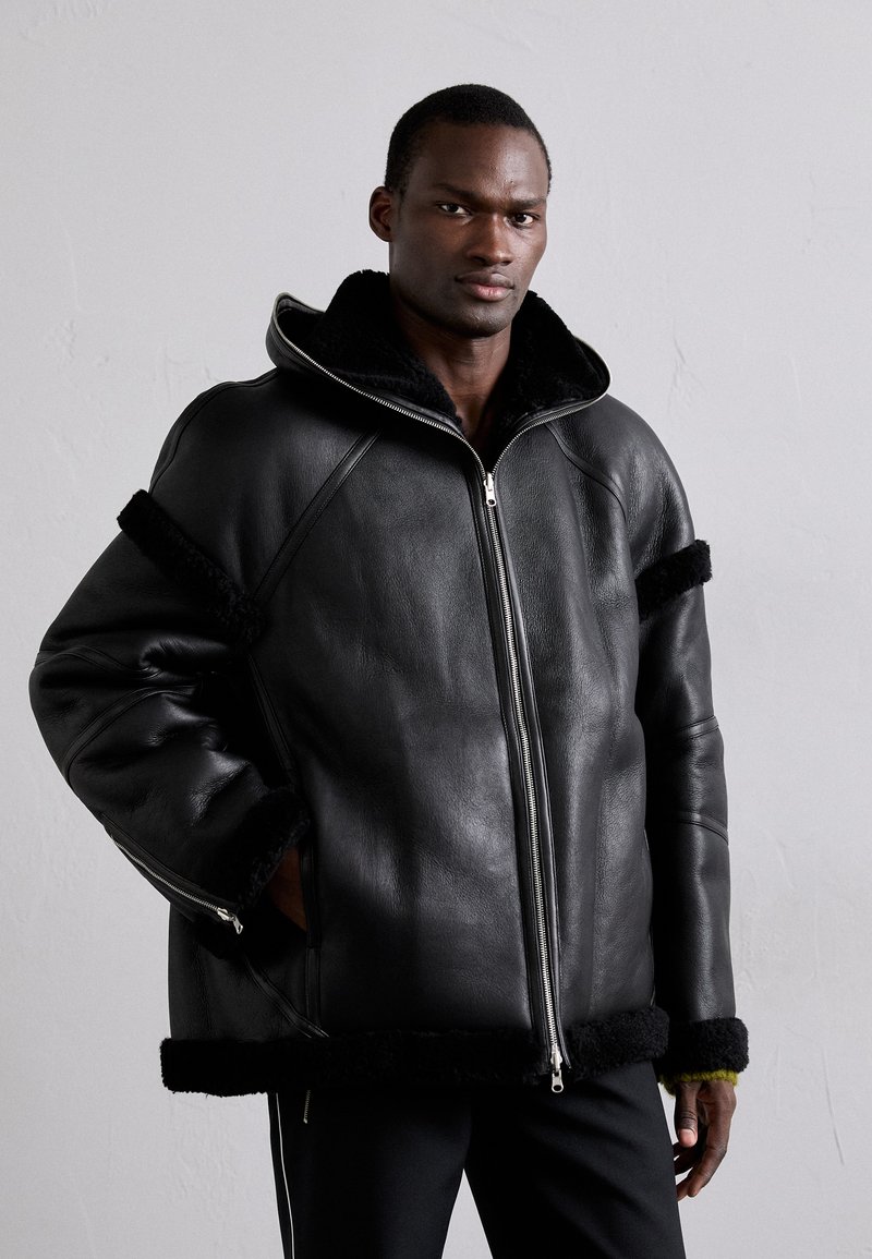 Black leather jacket with a fur-lined collar, featuring zippered front, side pockets, and black fur accents on sleeves and hem.