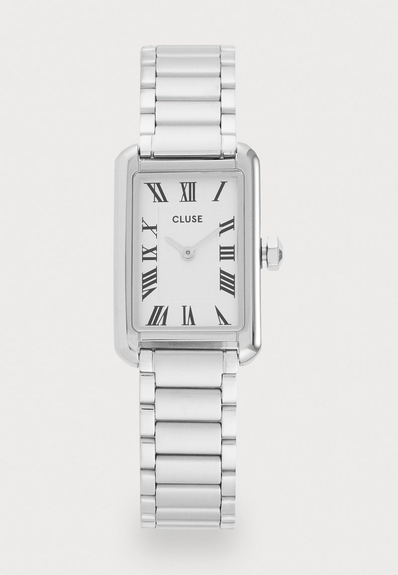 Stříbrné obdélníkové hodinky s leštěným kovovým páskem. Bílý ciferník obsahuje černé římské číslice a jednoduchý dvouručičkový mechanismus.