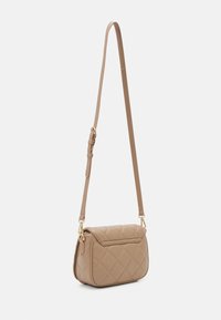Borsa a tracolla trapuntata color beige con tracolla regolabile e accenti in hardware dorato. Forma rettangolare compatta con chiusura a patta.
