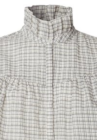 Camicia a scacchi bianca e grigia con colletto alto plissettato, chiusura con bottoni e dettagli plissettati sul décolleté e in vita. Tessuto leggero.