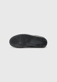 Sort sneaker sål med en struktureret gummioverflade og et mønstret dæk for greb og holdbarhed. Markant branding præget på siden.