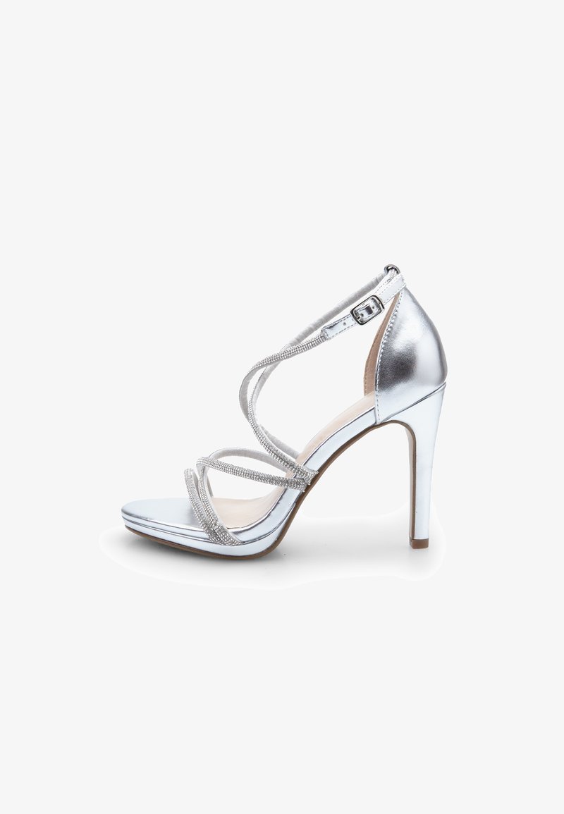 Silver high-heeled sandal with crisscrossed straps, metallic finish, open toe, and ankle buckle. Smooth texture with subtle shine.