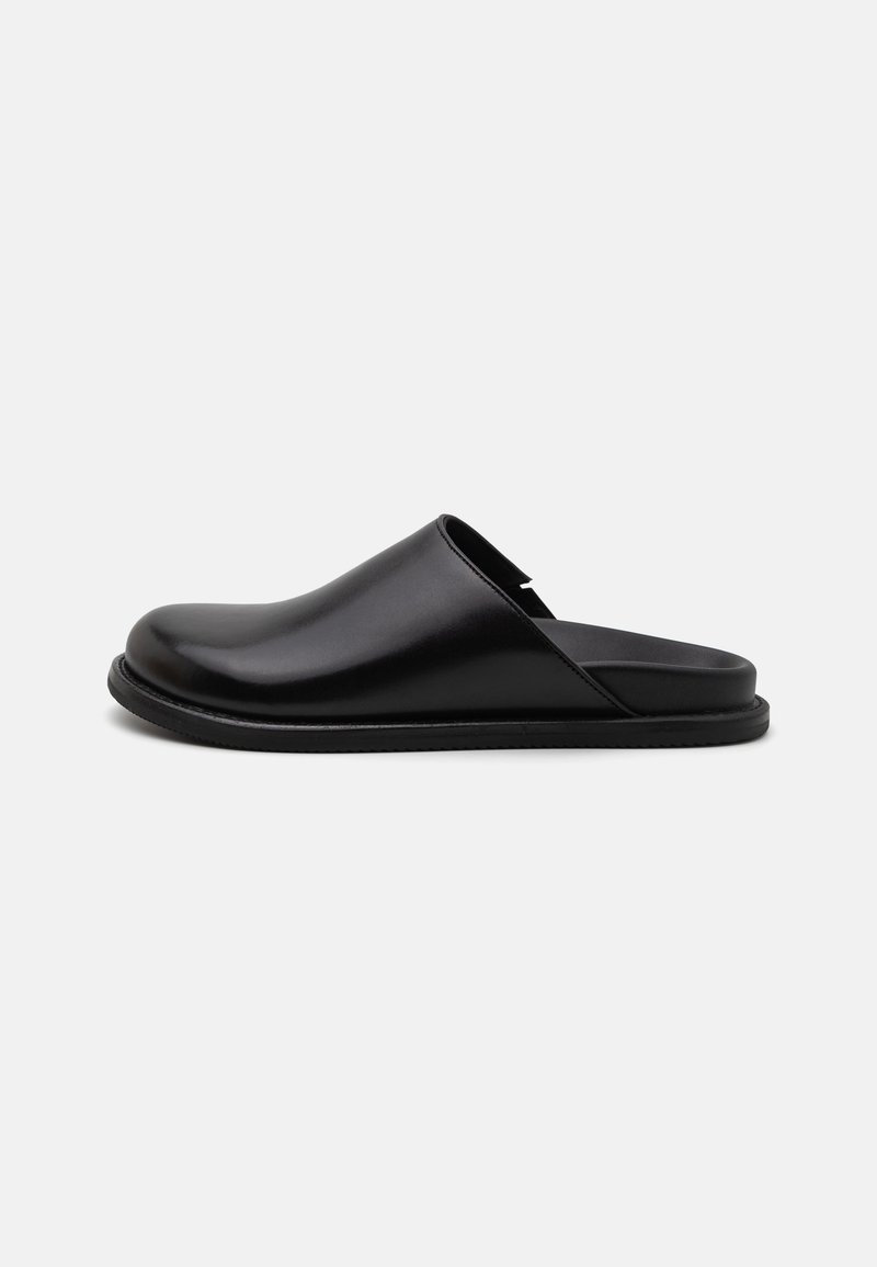 Sorte skinnlignende slip-on-sko med en glatt overflate, rund tå og minimalistisk design. Har en flat gummisåle for komfort.