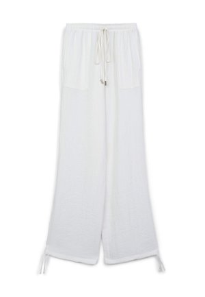Weiße Leinenhosen mit einem Kordelzugbund, zwei vorderen Taschen, weitem Bein-Design und Bindebändern an den Knöcheln. Weiche Textur mit feiner Naht.