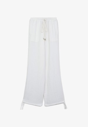 Weiße Leinenhosen mit einem Kordelzugbund, zwei vorderen Taschen, weitem Bein-Design und Bindebändern an den Knöcheln. Weiche Textur mit feiner Naht.