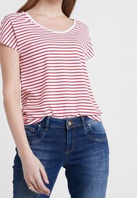Camiseta de manga corta a rayas horizontales rojas y blancas con cuello redondo, combinada con un pantalón de mezclilla azul. Tejido suave, corte casual.