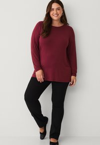 Burgundy long-sleeve top with a round neckline, paired with black pants and black flat shoes, featuring a relaxed fit and smooth texture.