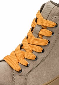 Hellgraue Wildleder-Stiefelette mit orangefarbenen synthetischen Schnürsenkeln, die durch schwarze Ösen gefädelt sind. Sie hat eine strukturierte Oberfläche und eine geschwungene Form.