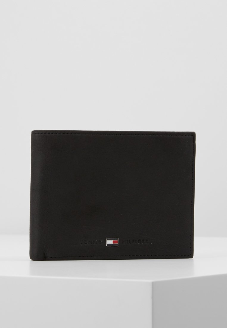 Svart skinnlommebok med et stilrent design, med tonalt søm og en liten Tommy Hilfiger-logo i rødt, hvitt og blått nederst.