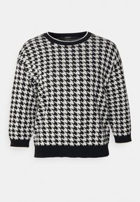 Pull en pied-de-poule noir et blanc, tissu en maille, encolure ronde, manches chauve-souris, accents noirs unis aux poignets et à l'ourlet.