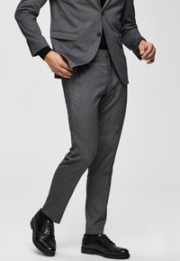 Gray suit pants made of smooth fabric, tailored fit, featuring a flat front and belt loops. Paired with black leather dress shoes.