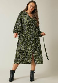 Vestido midi negro con un vibrante patrón verde, escote en V, mangas largas y una abertura lateral. Incluye un cinturón de tela a juego para ajuste.