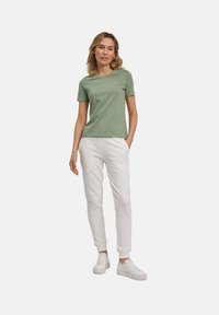 Groene katoen t-shirt gecombineerd met witte joggingbroeken. De outfit heeft een eenvoudig ontwerp en een relaxte pasvorm, aangevuld met witte sneakers.