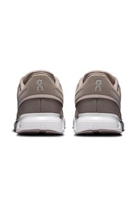 Beige athletic shoes feature a breathable mesh upper, rubber sole, and white accents, showcasing a rounded shape and textured surfaces.