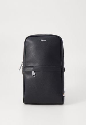 Juodas sintetinis medžiagos kuprinė, stačiakampio formos, su tekstūruotu paviršiumi, sidabriniais akcentais, priekinė zipui atidaroma kišenė ir logotipo detalė.