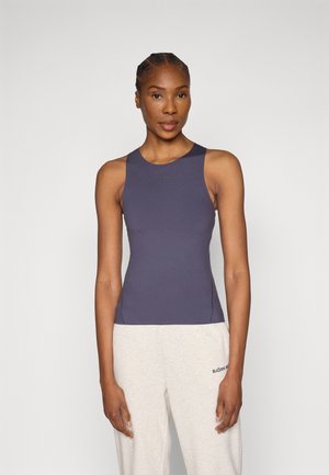 Tumesinine varrukateta topp, istuva lõikega, valmistatud siledast kangast. Omab ümarat kaelust ja tagasihoidlikku rinnaesist brändi.