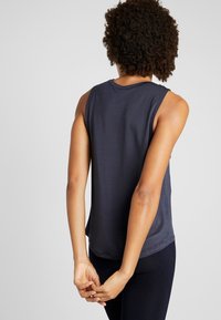 Top senza maniche di un blu navy scuro, realizzato in tessuto morbido e leggero. Collo tondo, vestibilità comoda, texture discreta e orlo curvo.