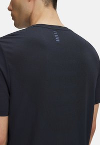 Camiseta deportiva azul marino con cuello redondo y mangas cortas, que presenta una tela texturizada y un detalle de líneas horizontales en la parte posterior.