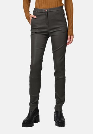 Pantalones de cuero negros ajustados con bolsillos laterales con cremallera y cierre de botón, combinados con botas negras de tacón grueso y un suéter marrón de canalé.