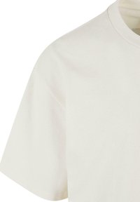 Ljus krämfärgad bomulls-t-shirt med rund halsringning, korta ärmar och en slät yta. Har en enkel design utan mönster eller accenter.