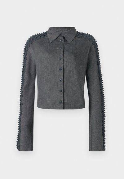 Cropped button-up shirt in dark grey fabric, featuring textured ruffled detailing along the sleeves and a classic collar.
