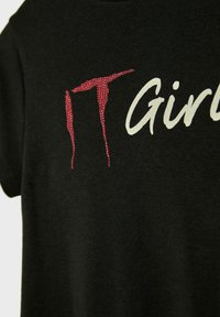 Czarna koszulka z napisem "IT" wysadzanym czerwonymi kryształkami i "Girls" w białej skryptowej czcionce na piersi.