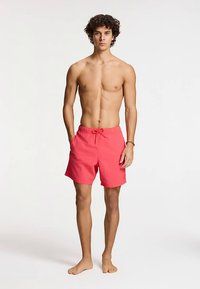 Erksad korallivärvi ujumisšortsid elastse vöökohaga ja paelaga kinnitusega. Valmistatud kerge kangast, millel on lõdvestunud lõige ja voodrita.