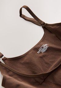 Bralette marron à bretelles réglables avec tissu doux et instructions de lavage imprimées à l’intérieur du panneau arrière.