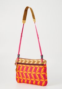 Geantă crossbody cu un model geometric în nuanțe de roz și portocaliu, margini din țesătură maro, curea roz detașabilă și închidere cu fermoar.