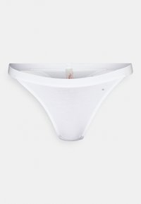 Hvit bomullstrang med en glatt tekstur, med tynne sidestrenger og et minimalistisk design. Inkluderer en liten logoaksent.