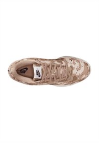 Nike sneakers in een lichtbruin camouflagepatroon, met een bovenkant van stof, vetersluiting en een witte rubberen zool.