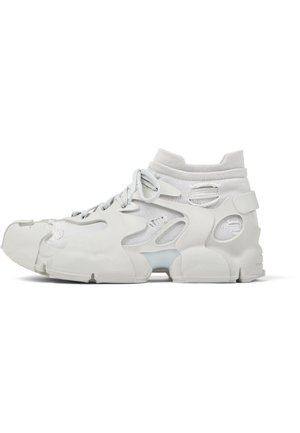 Baskets montantes blanches avec semelle épaisse, tissu mesh, trous découpés, lacets à l'avant et col de cheville semblable à une chaussette.