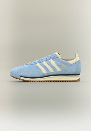 Baskets Adidas SL 72 en daim bleu clair avec des rayures crème, languette au talon et semelle en gomme, présentées de profil sur un fond neutre.