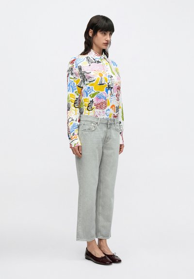 Chemise à manches longues avec un imprimé multicolore sur fond blanc. Jean gris clair à jambes larges. Ballerines bordeaux avec un détail de nœud.