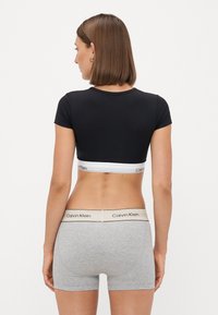 Svart kortermet t-skjorte med hvit Calvin Klein-bånd, kombinert med grå boxershorts med svart midjebånd.