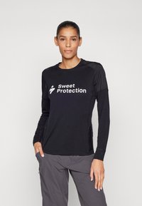 Must musta varrukatega särk, millel on valge "Sweet Protection" logo. Valmistatud pehmest materjalist, sobitava disaini ja küljetaskutega.