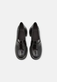Black leather loafers with a rounded toe, strap accent, and rubber sole. Smooth texture with a glossy finish. CAMPer logo visible inside.