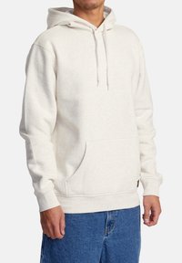 Haut en hoodie beige clair en tissu doux, avec une poche kangourou, une capuche avec cordon de serrage ajustable et des poignets et un ourlet côtelés.