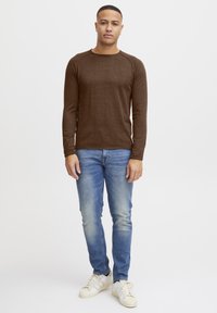 Brun langermet skjorte med rund hals, kombinert med lyseblå jeans og off-white sneakers. Strukturert stoff med en tettsittende fasong.