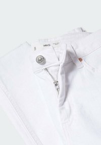 Jean blanc plié avec fermeture éclair partiellement ouverte et bouton visible, montrant l'étiquette de la marque MNG et les détails de la taille.