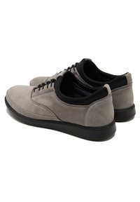 Graue Wildlederschuhe mit glatter Oberfläche, runder Zehenpartie und schwarzer Gummisohle. Verfügt über schwarze Textilakzente um den Kragen und die Schnürung.