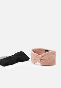 To stoffhodebånd: ett svart med knutedesign, og ett rosa med teksturert strikk og sløyfe. Begge er myke og elastiske.