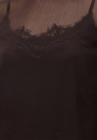 Haut noir sans manches avec fines bretelles et un bord en dentelle le long de l'encolure, fabriqué en tissu léger légèrement texturé.