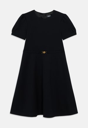 Black dress with short puff sleeves, detailed with a gold circular belt buckle at the waist and a concealed back zipper.