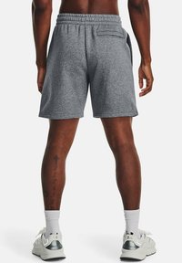 Grå, elastiska idrottsshorts med midjeresår, bakficka och sidofickor, tillverkade av textilmaterial. Ikoniskt med vita strumpor och grå sneakers.