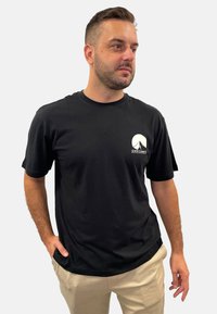 Black cotton t-shirt with short sleeves, featuring a white graphic of a mountain and text "SEVEN SUMMITS" on the left chest.